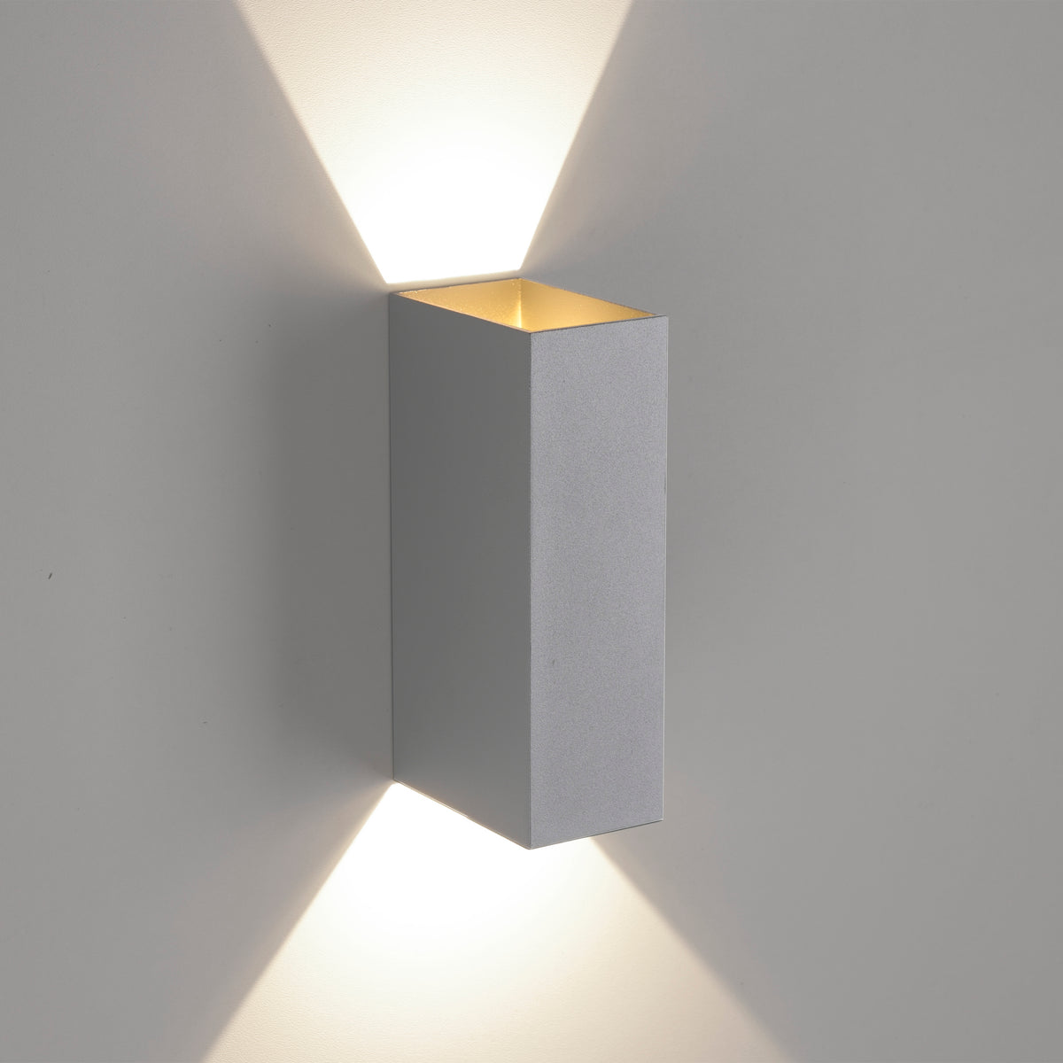 Applique fixée au mur projetant deux faisceaux lumineux vers le haut et le bas.