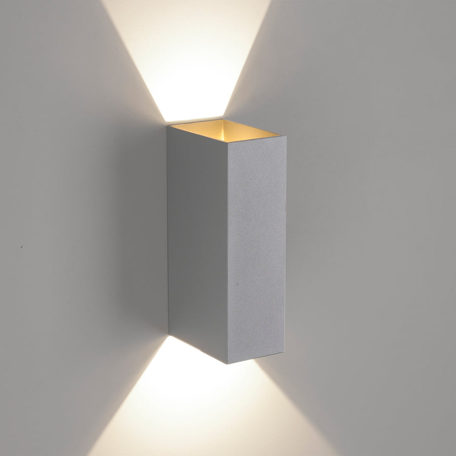 Applique fixée au mur projetant deux faisceaux lumineux vers le haut et le bas.