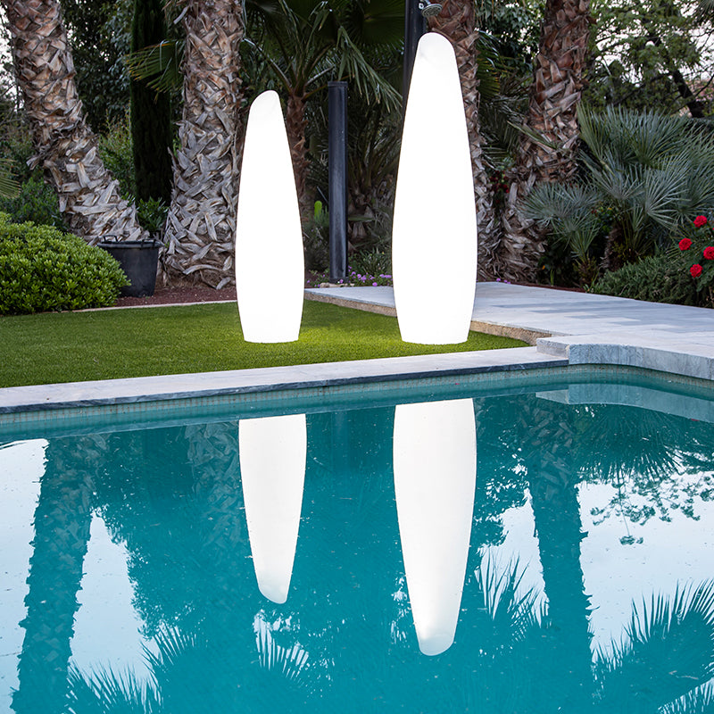 Deux lampadaires éclairés bordent une piscine, leurs reflets blancs dans l'eau bleue