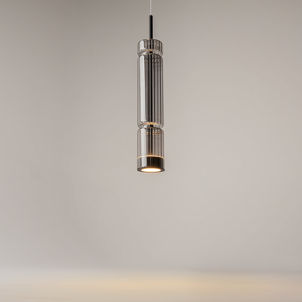 Vue rapprochée du luminaire allumé, verre cylindrique cannelé et reflets lumineux