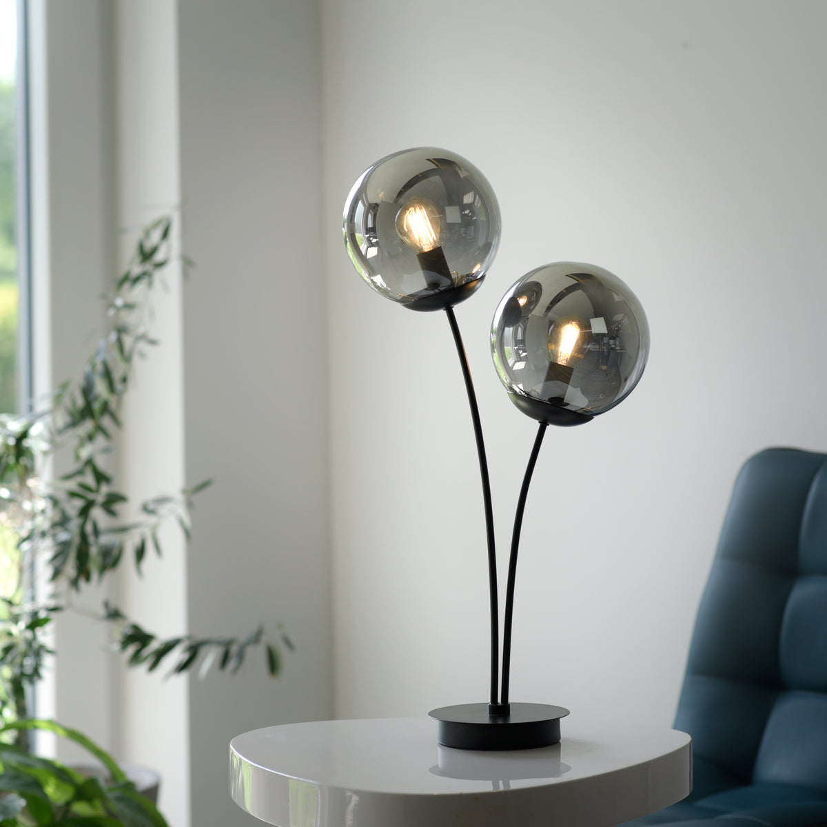 Mise en ambiance sur table blanche, près d'une plante verte et fauteuil