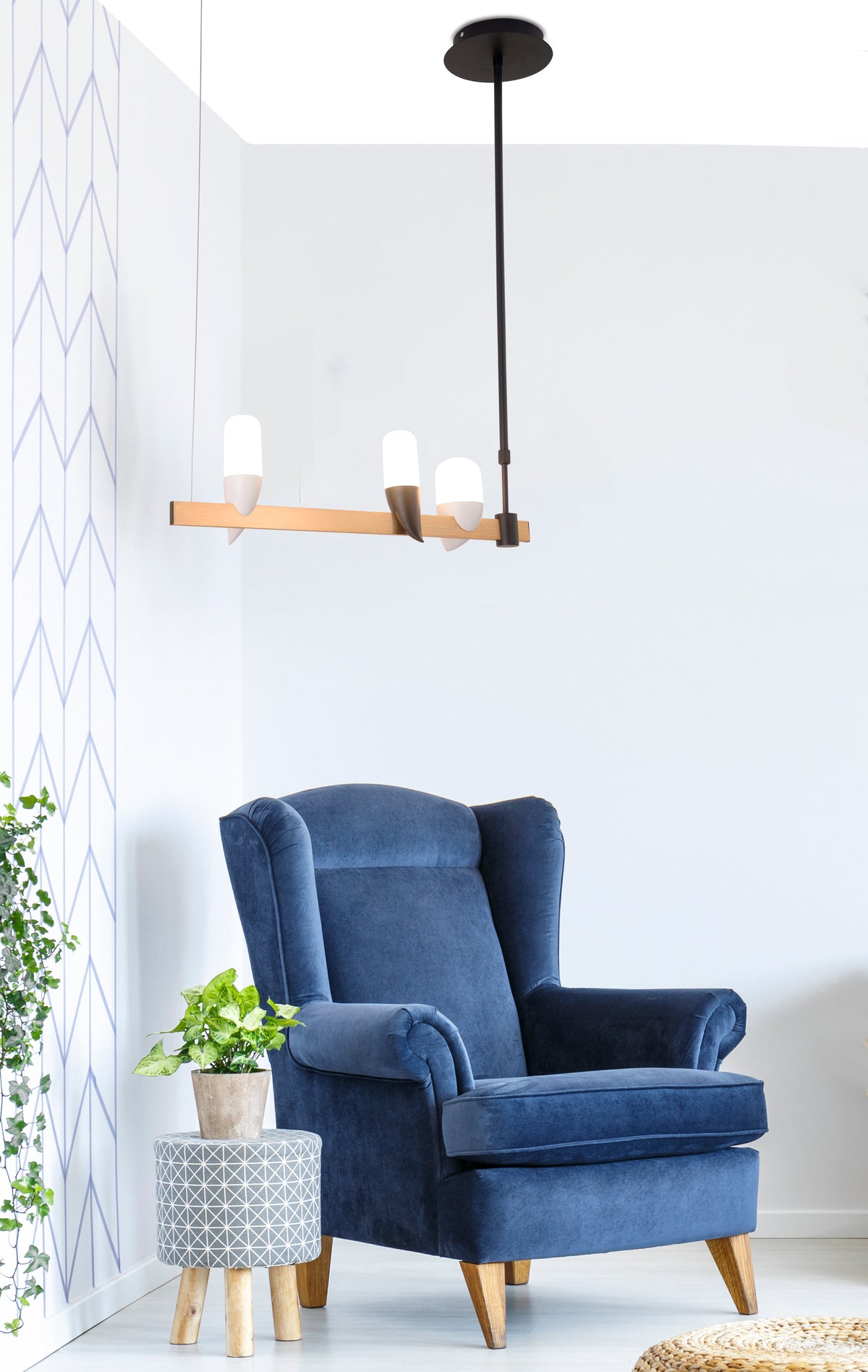 Mise en ambiance dans un salon avec fauteuil bleu, plante verte et luminaire suspendu