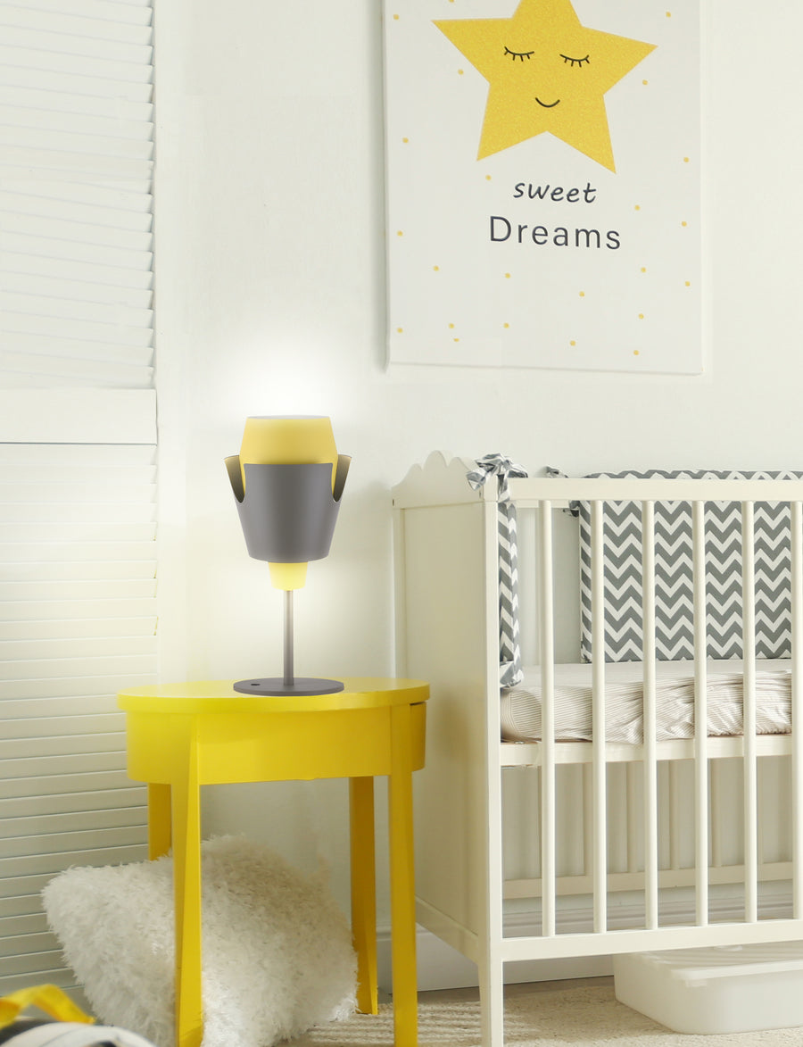 Lampe allumée posée sur une table de chevet jaune dans une chambre d'enfant