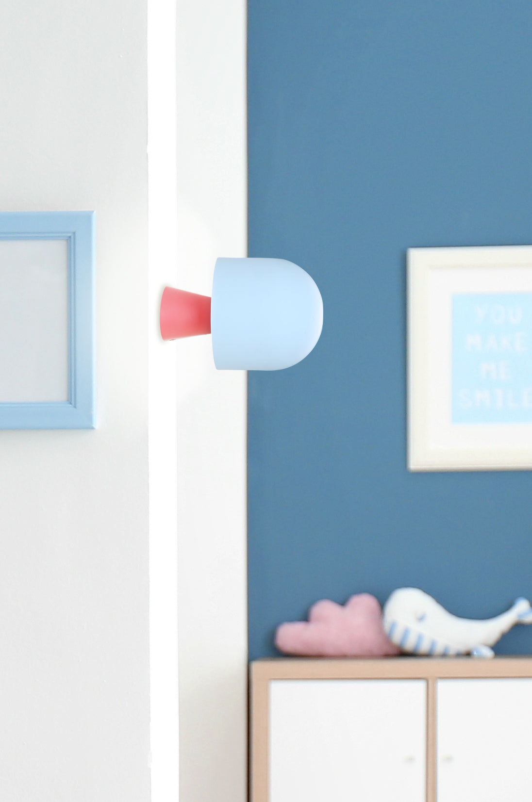 Applique murale bleue et rouge installée dans une chambre d'enfant au mur bleu