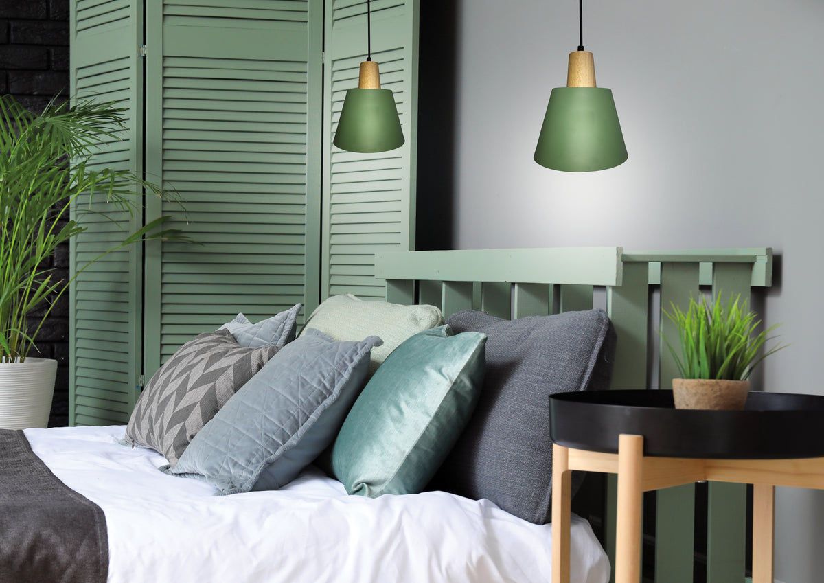 Ambiance chambre cosy avec deux suspensions vertes allumées au-dessus de coussins et paravent