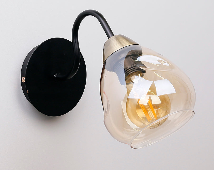 Gros plan sur l'ampoule à filament et le verre ambré de l'applique murale.