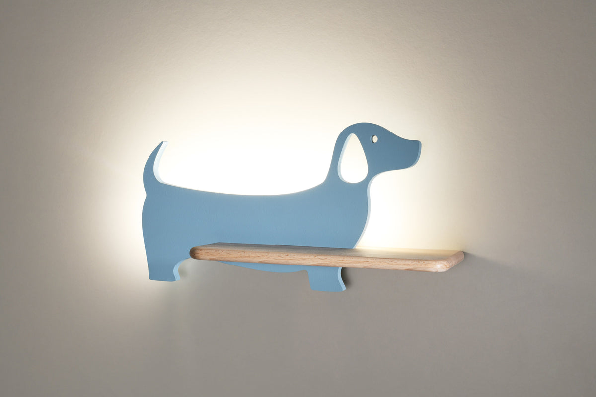 Applique bleue allumée contre un mur beige, halo lumineux diffus autour du chien