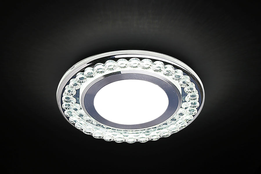 Spot LED allumé dans le noir, halo blanc central et reflets sur les verres
