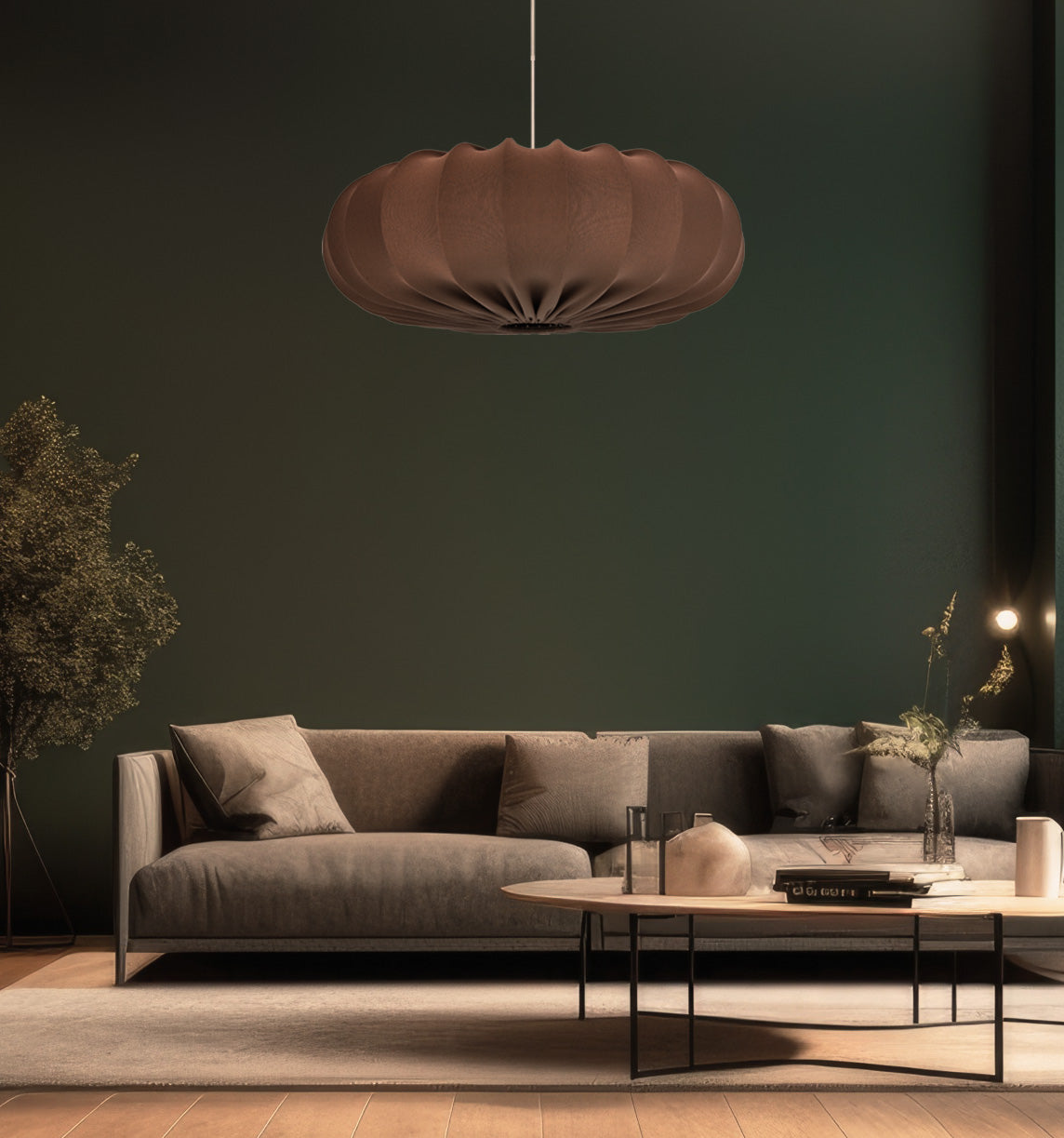 Mise en ambiance dans un salon vert foncé avec canapé gris et suspension allumée.