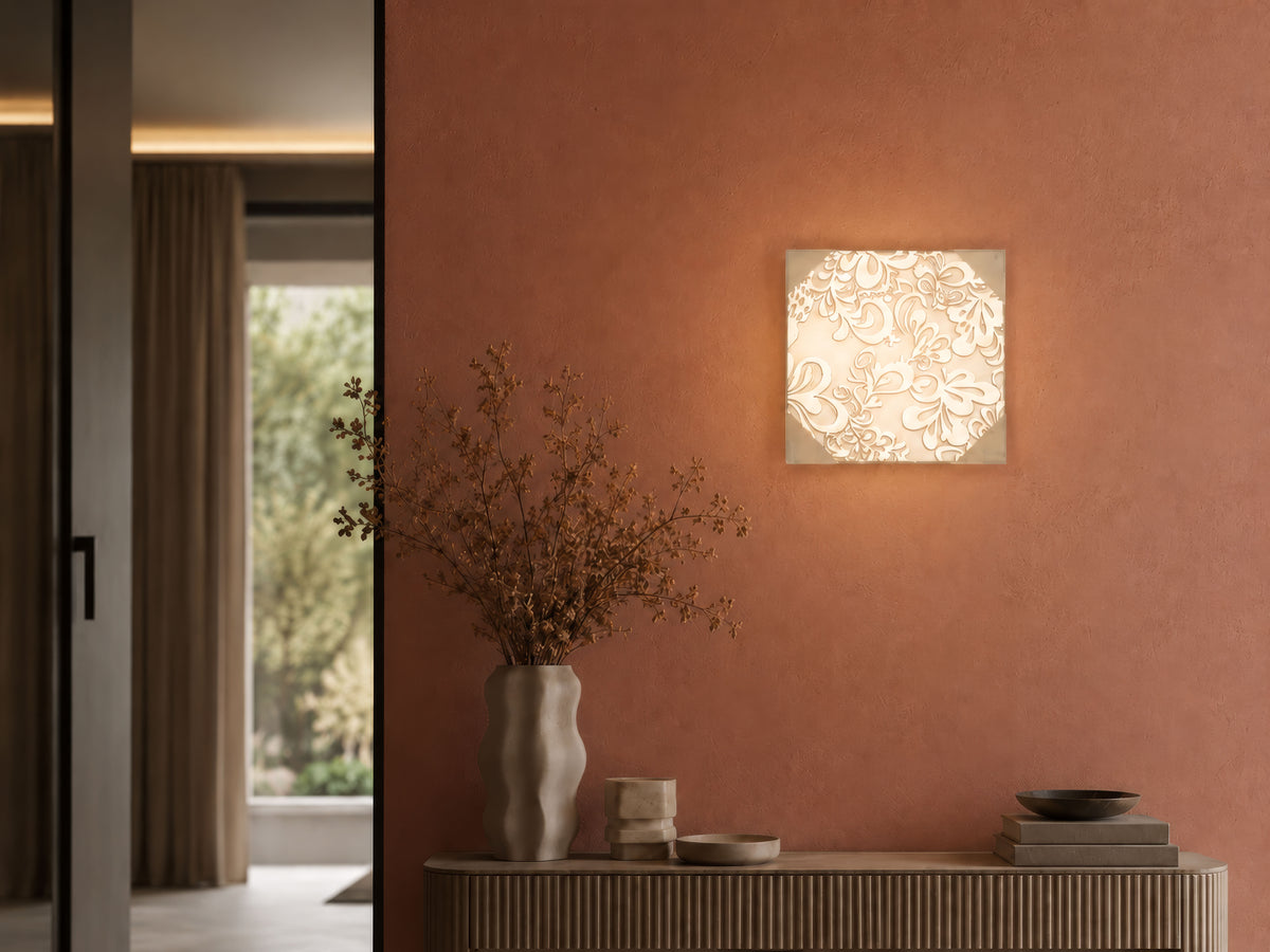 Luminaire allumé fixé au mur terracotta, au-dessus d'un meuble et de fleurs séchées
