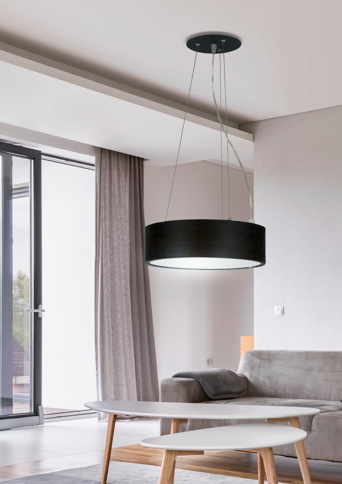 Mise en ambiance du salon : suspension allumée au-dessus de tables basses et canapé.