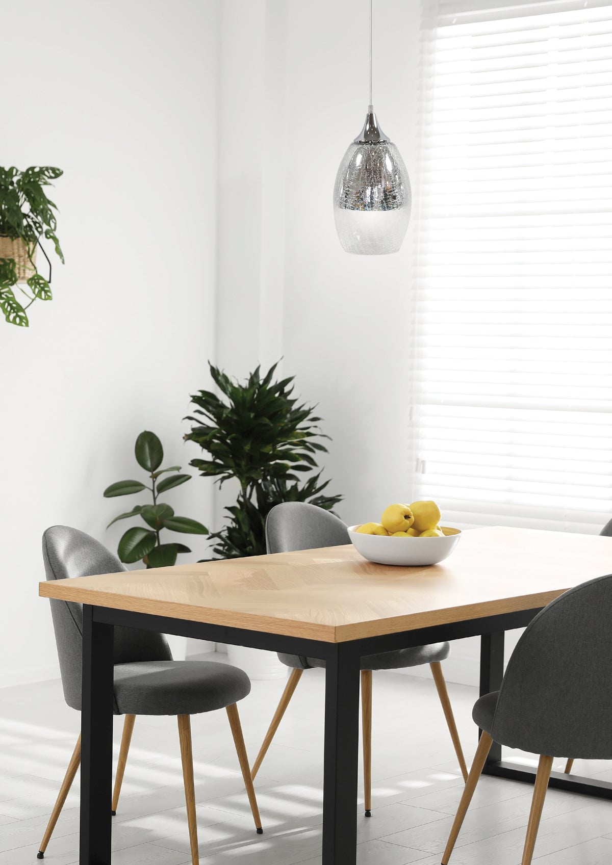 Mise en ambiance : suspension allumée au-dessus d'une table à manger en bois clair