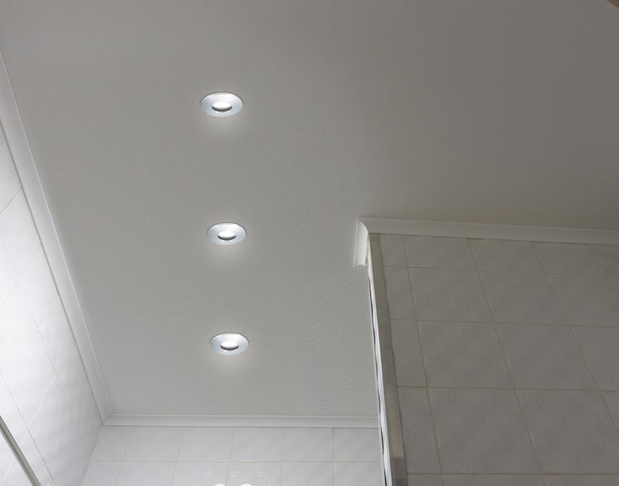 Vue en contre-plongée des trois spots encastrés au plafond, halos lumineux blancs