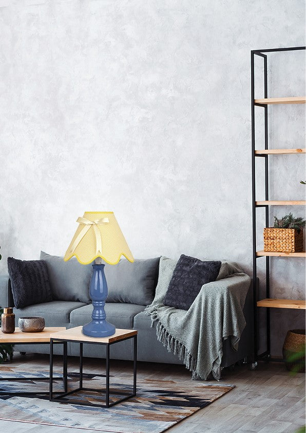 Mise en ambiance salon, lampe bleue allumée sur table basse devant canapé gris