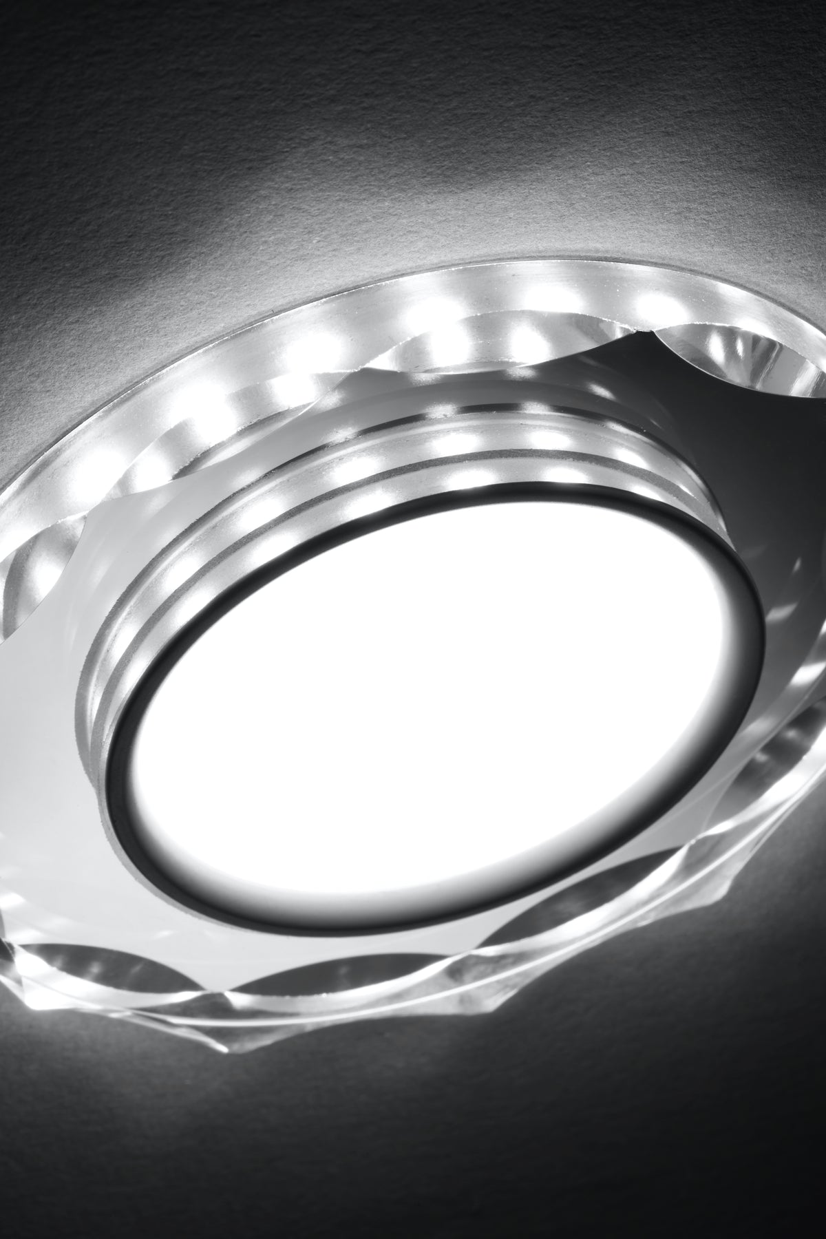 Détail rapproché de la finition en verre facetté et des LED allumées autour du diffuseur.