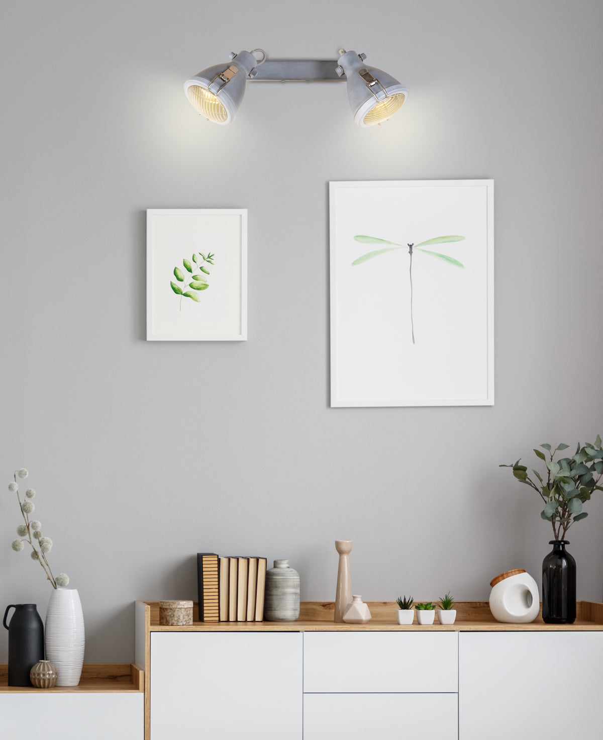Mise en ambiance murale du luminaire allumé au-dessus d'un meuble et de cadres