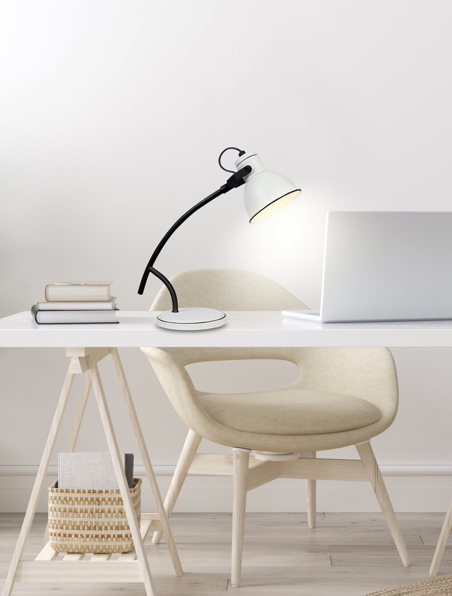 Lampe allumée sur un bureau avec ordinateur portable et livres.