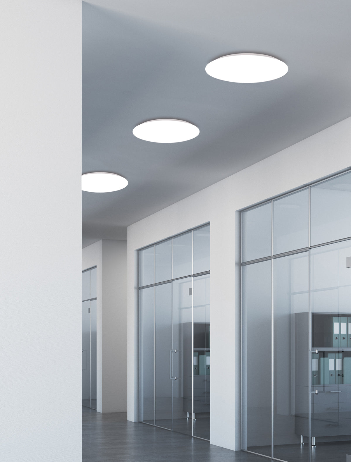 Mise en ambiance de trois plafonniers ronds allumés dans un couloir de bureaux