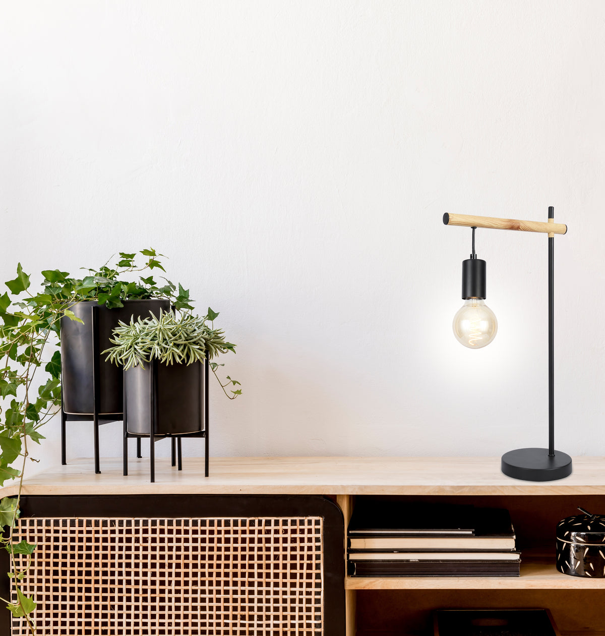 Lampe allumée en situation sur un meuble en bois, près de plantes vertes