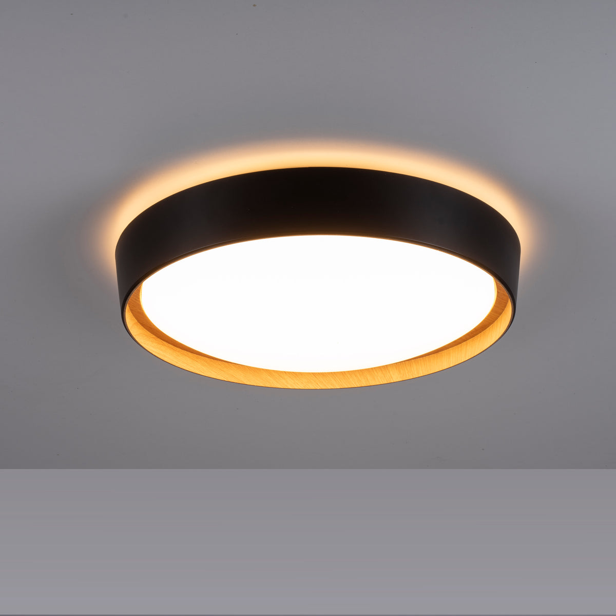 Plafonnier allumé au plafond diffusant un halo lumineux chaud périphérique