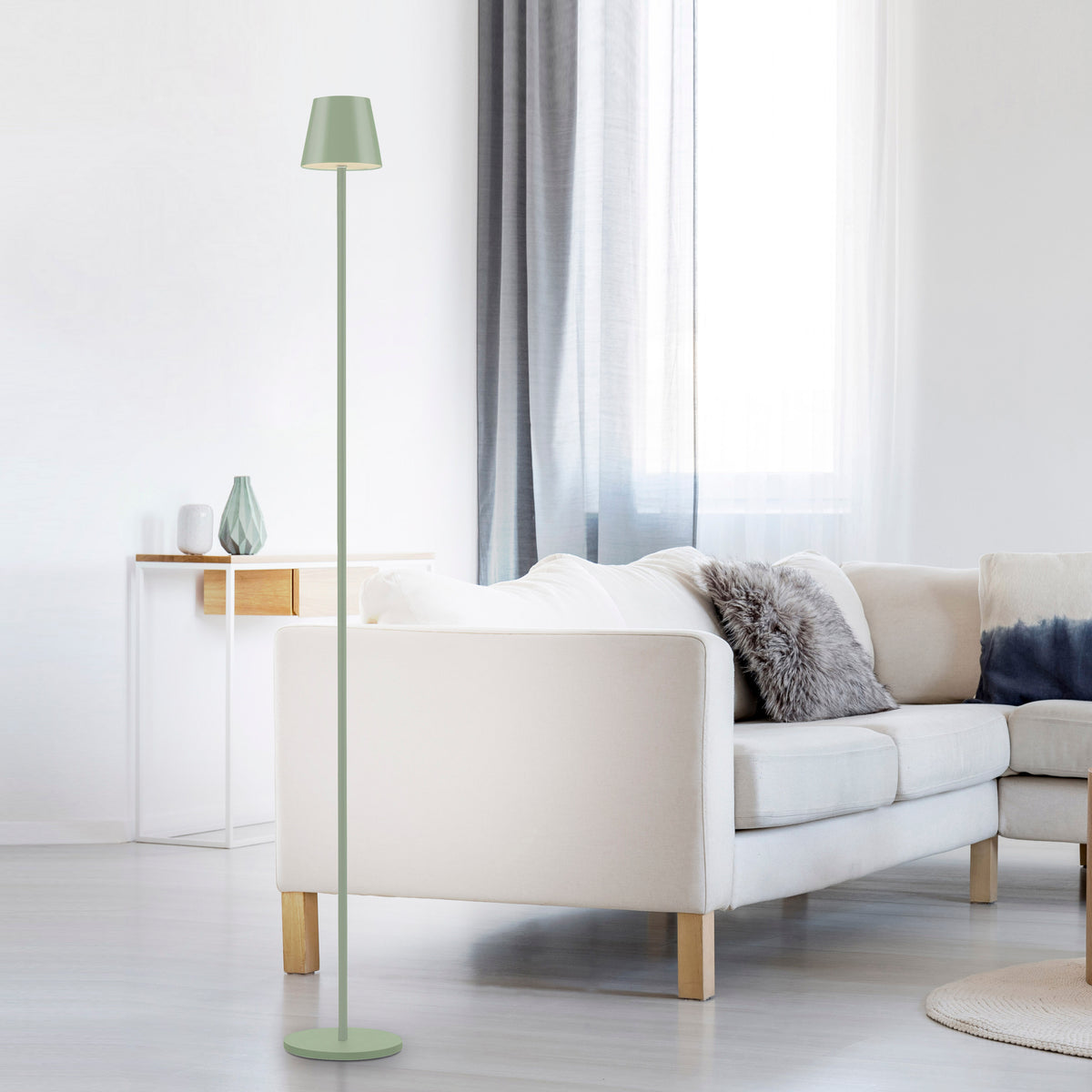 Lampadaire vert installé dans un salon clair près d'un canapé beige