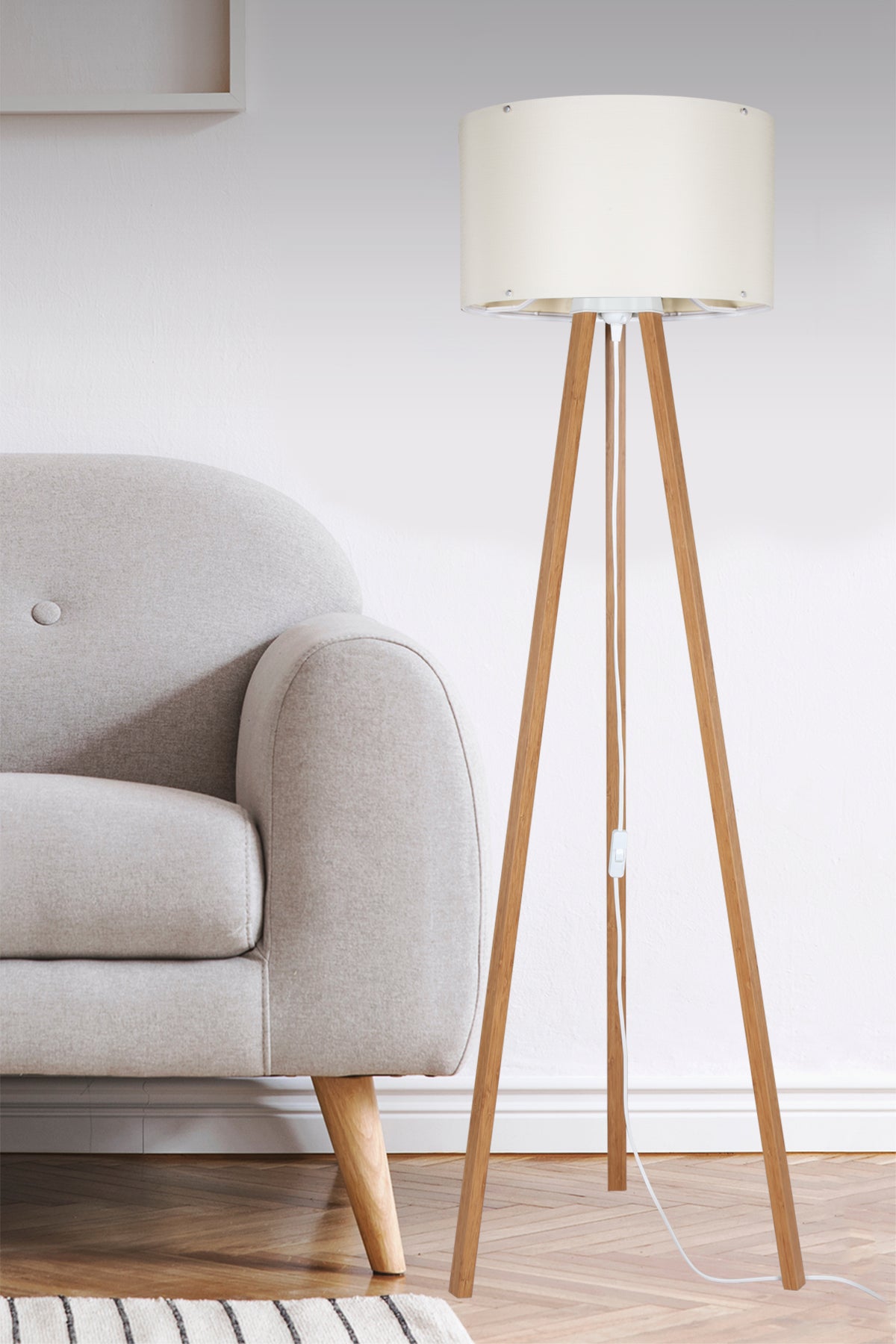 Lampadaire en bois et abat-jour crème installé près d'un fauteuil dans un salon.