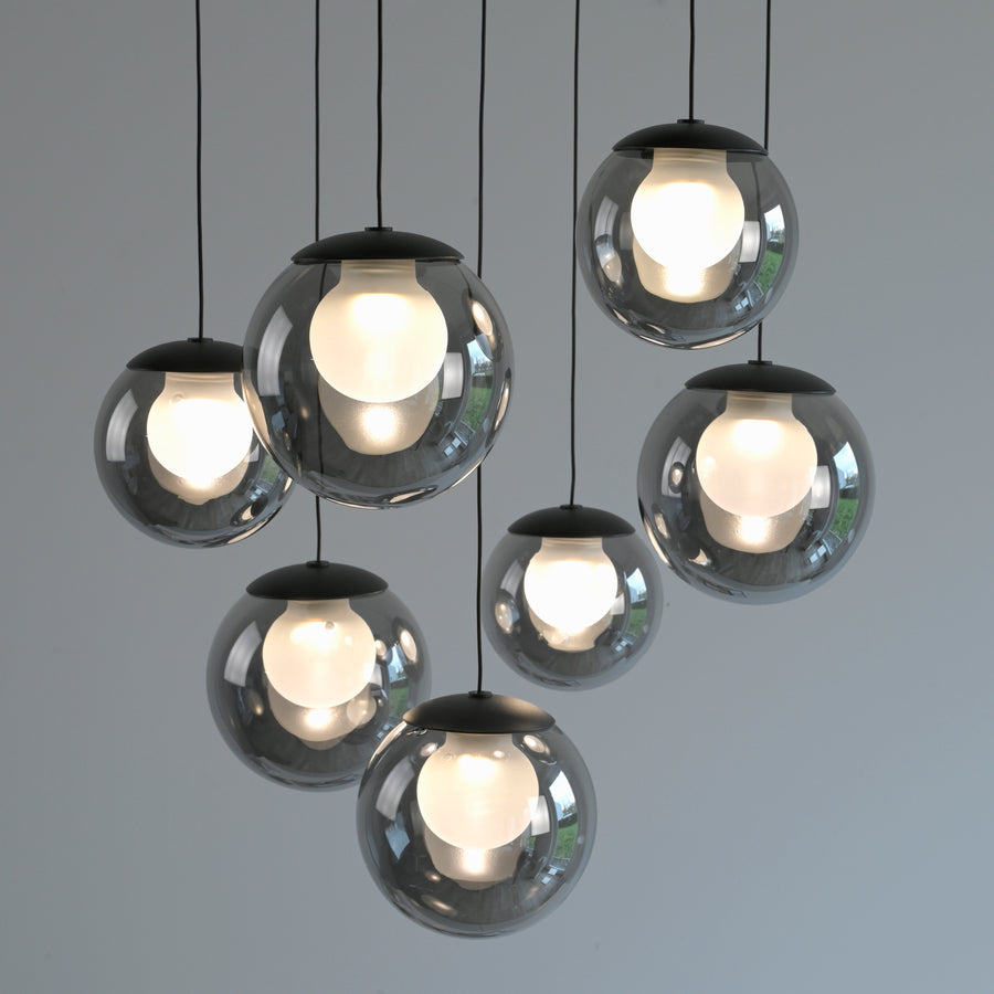 Suspension à sept globes en verre fumé allumés, suspendus à des hauteurs variables.
