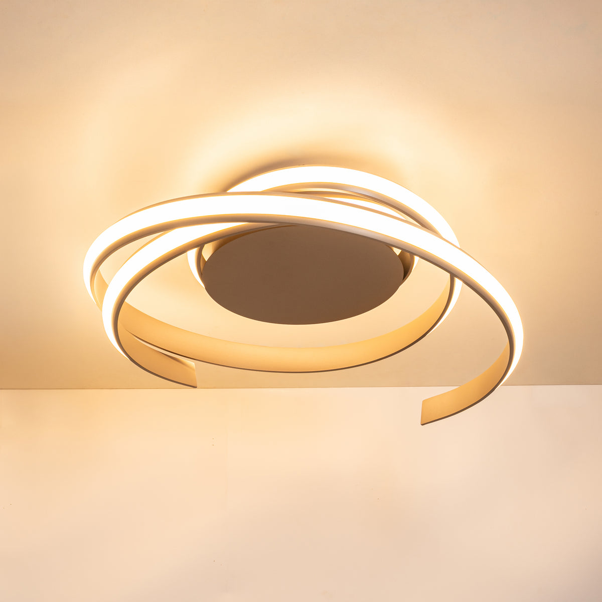 Plafonnier beige éclairé en lumière chaude, diffusant une lueur dorée au plafond.