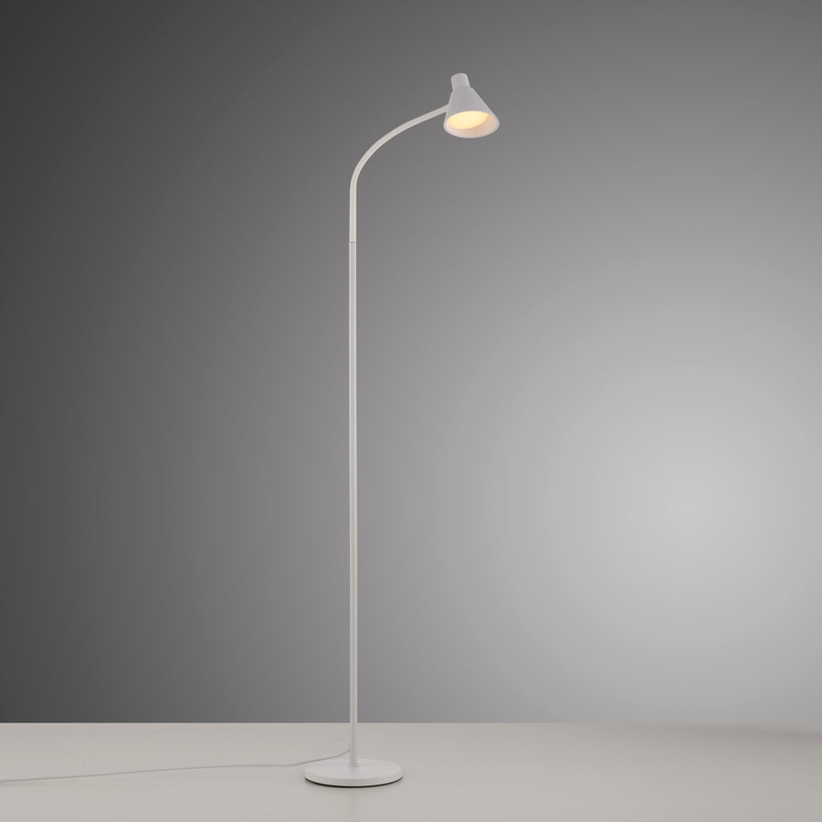 Lampadaire allumé dans une pièce grise, halo de lumière chaude vers le sol