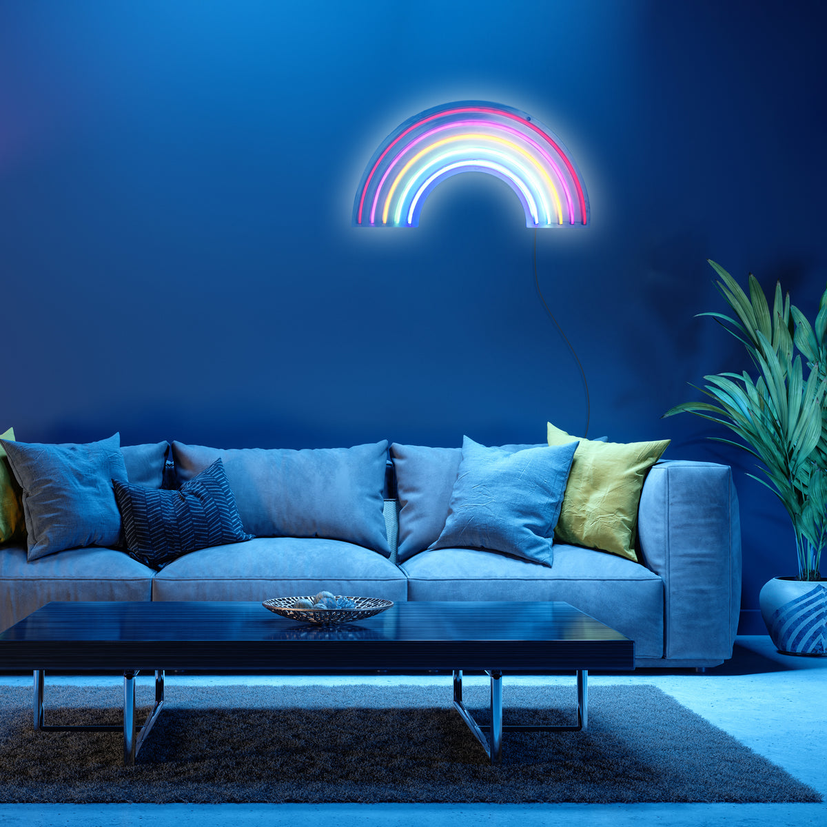 Mise en ambiance dans un salon bleu nuit, applique arc-en-ciel murale allumée au-dessus du canapé.