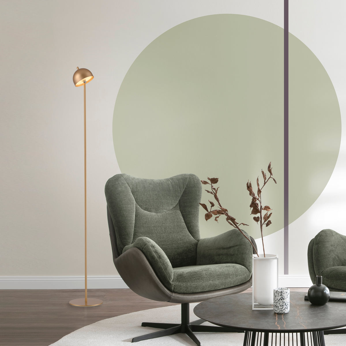 Mise en ambiance salon avec fauteuil vert, table basse et lampadaire allumé