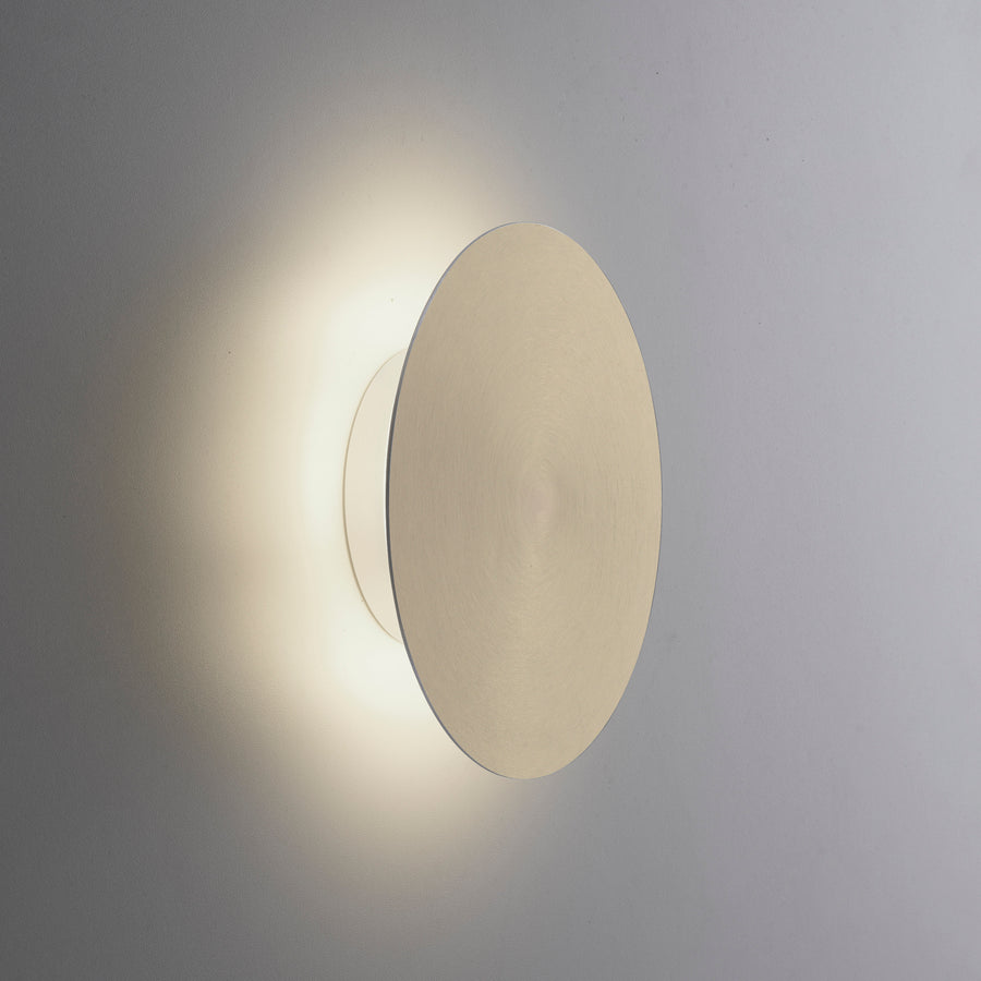 Détail de la finition laiton mat éclairée, halo lumineux diffus sur le mur