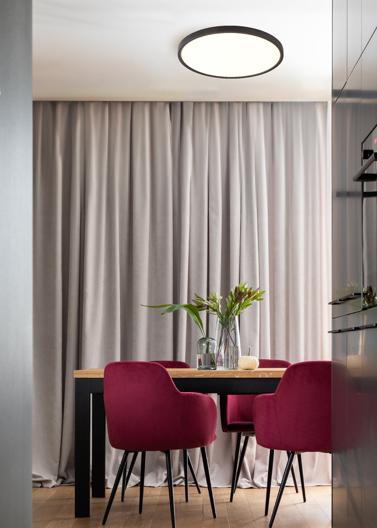 Vue en situation dans un intérieur contemporain, plafonnier éclairant table en bois et chaises velours