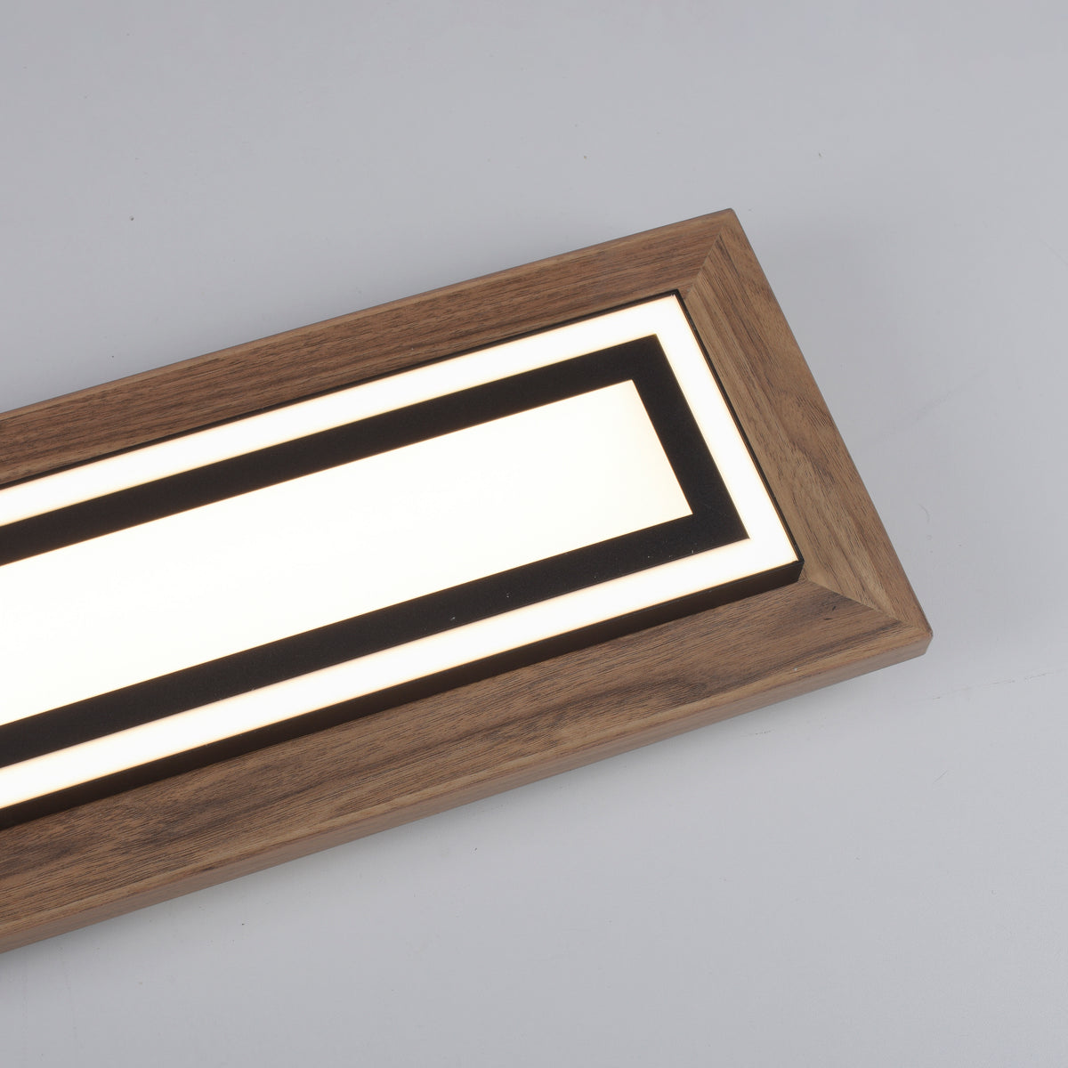 Gros plan sur l'angle du cadre en bois et le diffuseur LED allumé.