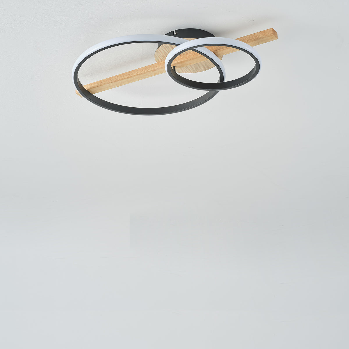 Luminaire éteint fixé au plafond, montrant les cercles noirs et la structure en bois