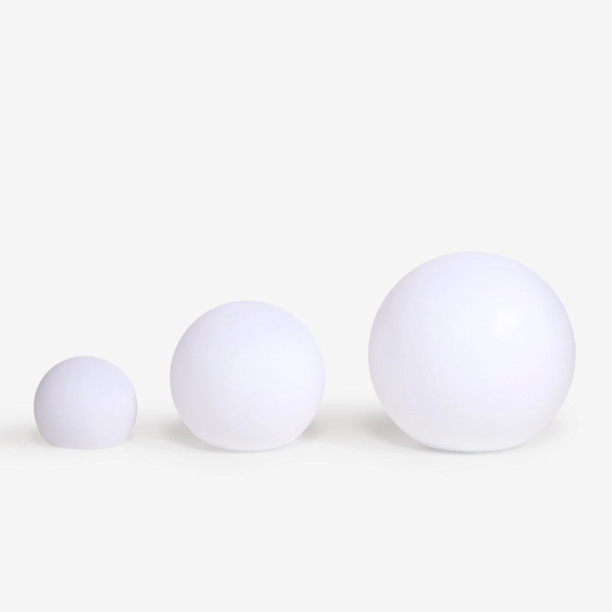Trois globes lumineux blancs de tailles différentes alignés pour comparer les dimensions