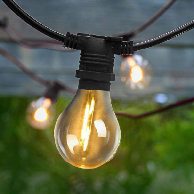Gros plan sur une ampoule à filament doré et sa douille noire sur câble noir