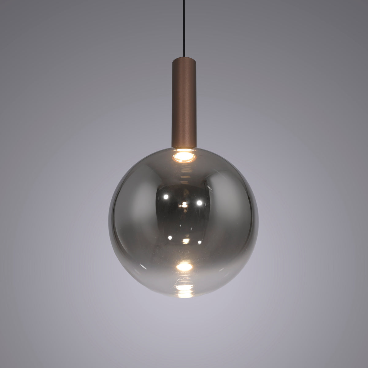 Gros plan sur la boule en verre fumé allumée, reflets et douille cuivrée visible.