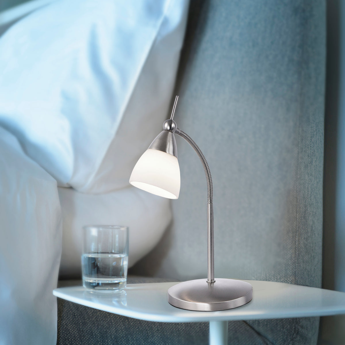 Lampe allumée posée sur une table de nuit dans une chambre, ambiance douce.