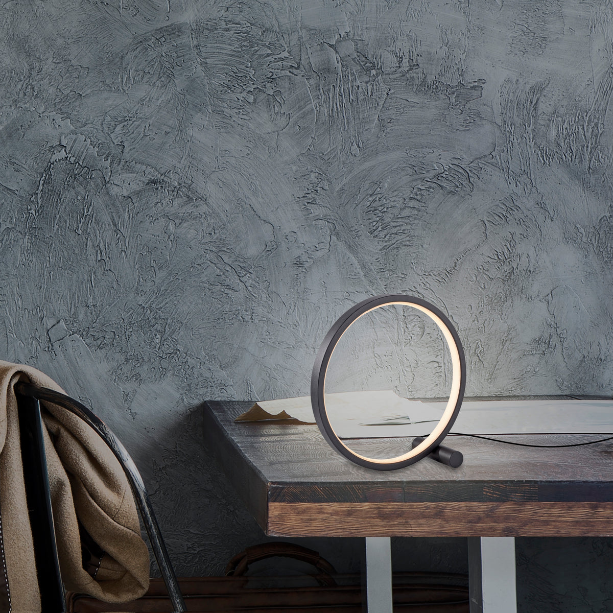Mise en ambiance sur table en bois, luminaire allumé contre mur gris texturé.