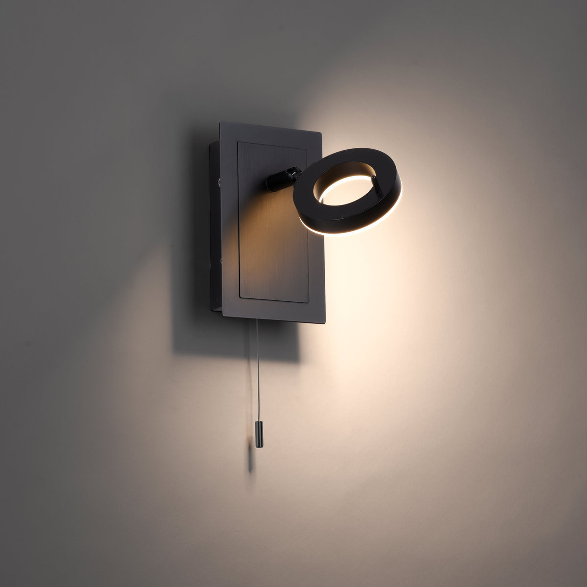 Vue de profil du luminaire fixé au mur, halo lumineux chaud sur fond sombre