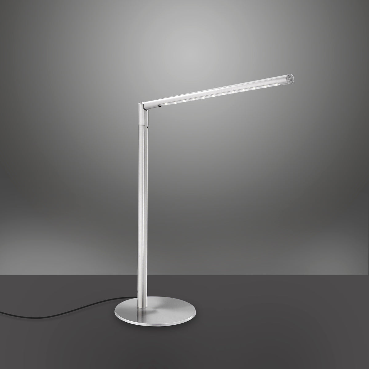 Luminaire argenté de trois quarts avec câble noir apparent sur fond dégradé sombre.