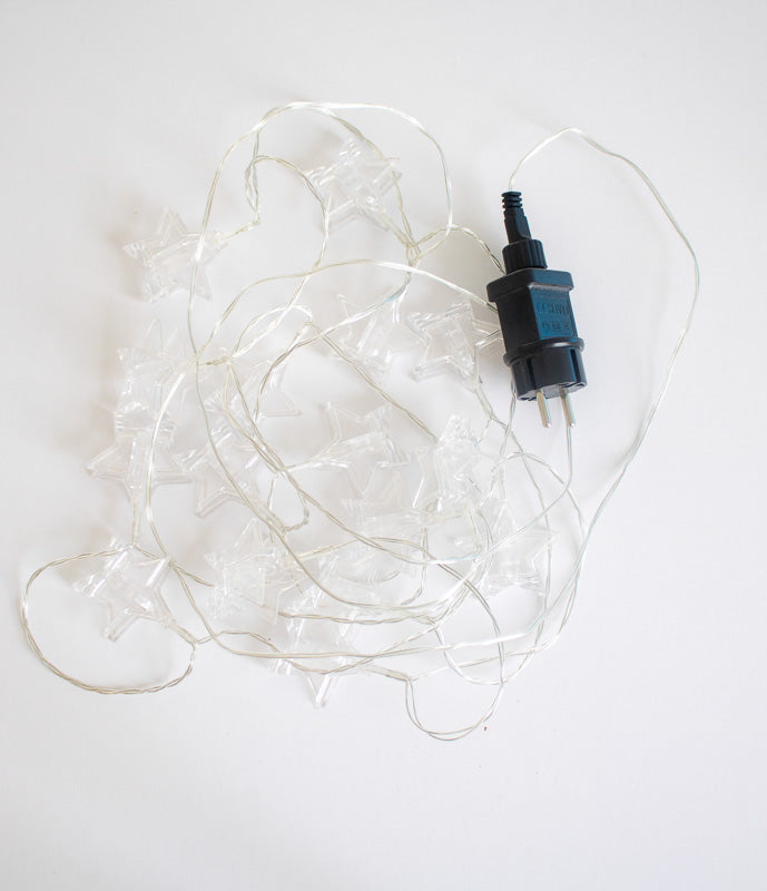 Produit éteint enchevêtré avec prise électrique noire à deux broches, fond blanc.