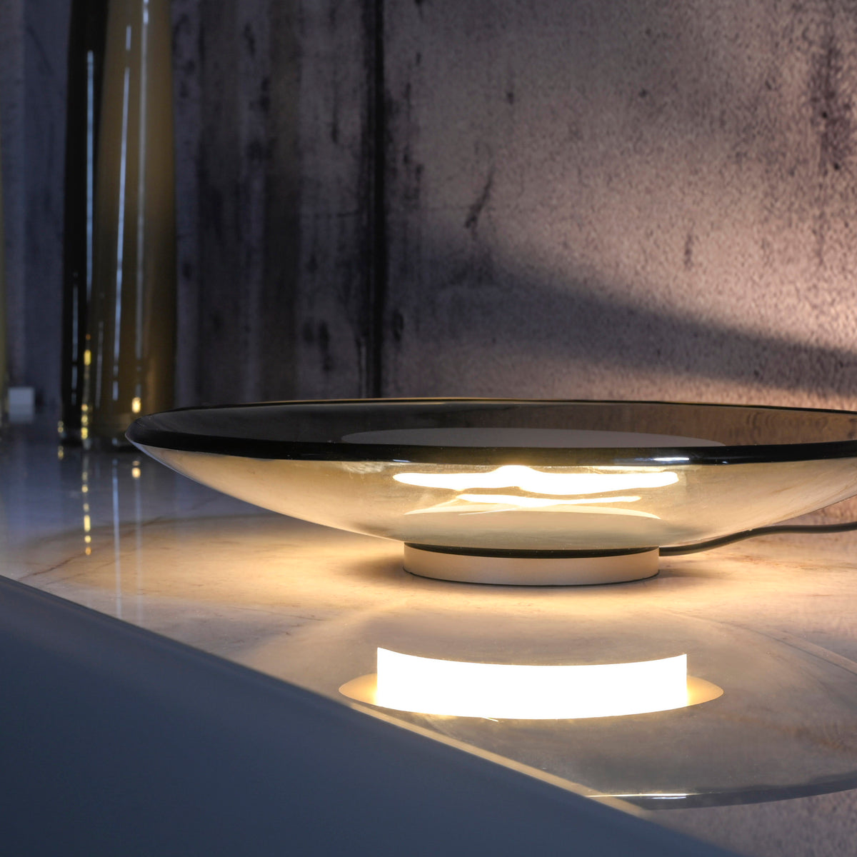 Lampe posée sur un marbre, éclairant la pièce d'une lumière chaude et tamisée.