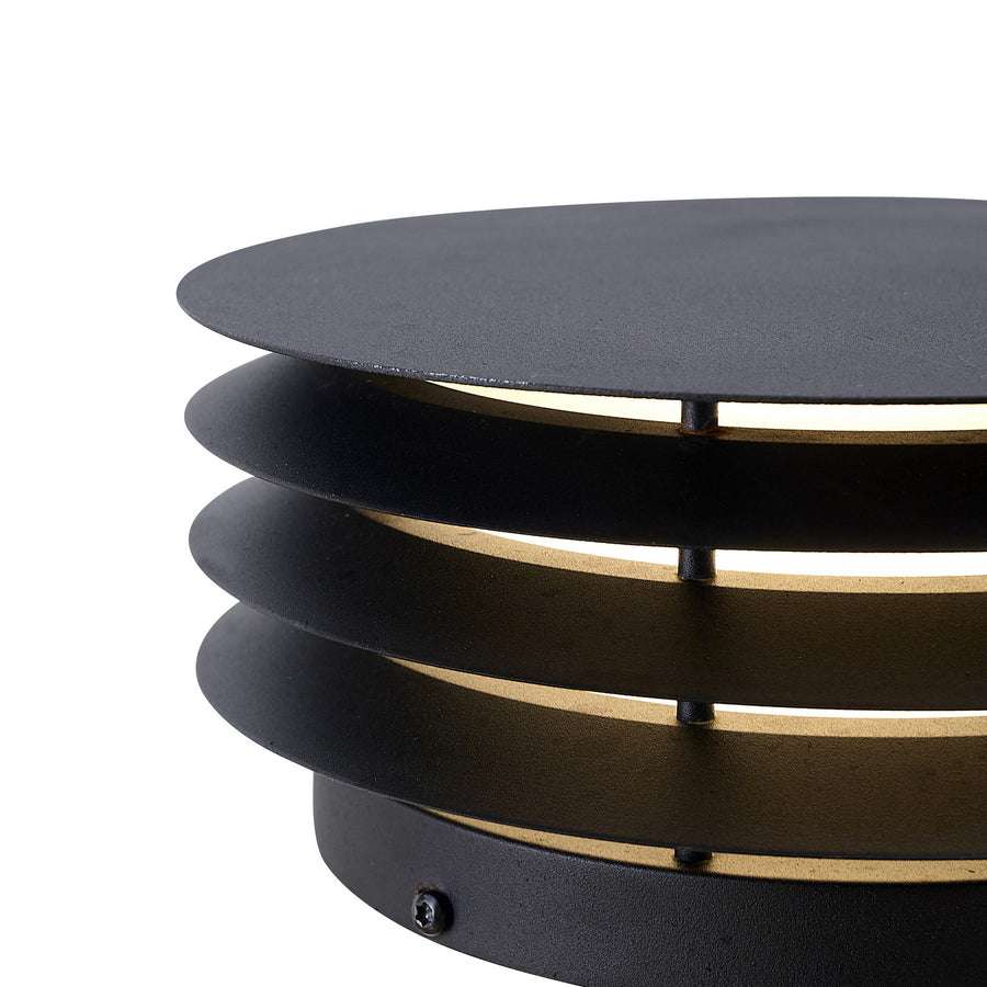 Détail rapproché des ailettes noires et vis de fixation du luminaire extérieur.