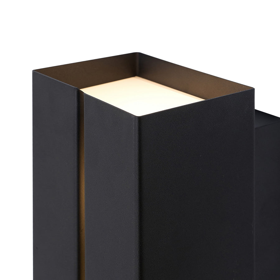 Détail du haut de l'applique montrant le diffuseur carré allumé dans le boîtier noir.