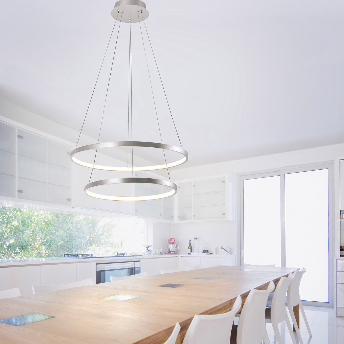 Mise en ambiance dans une cuisine blanche, suspension allumée au-dessus d'une grande table