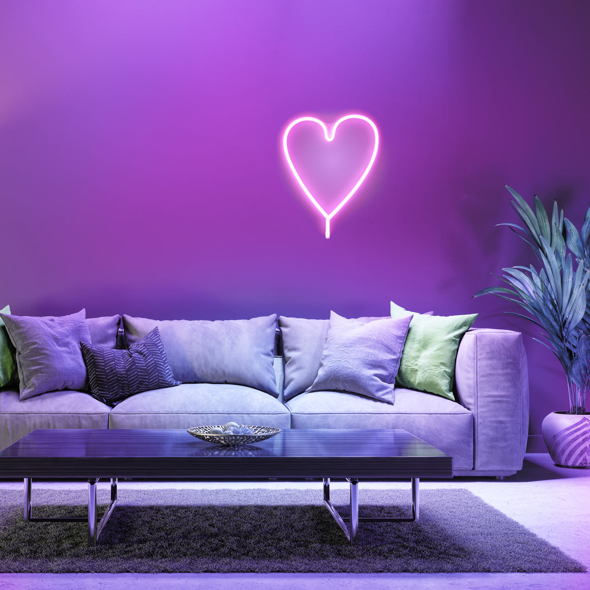 Mise en ambiance : cœur néon rose lumineux fixé au mur violet au-dessus d'un canapé.