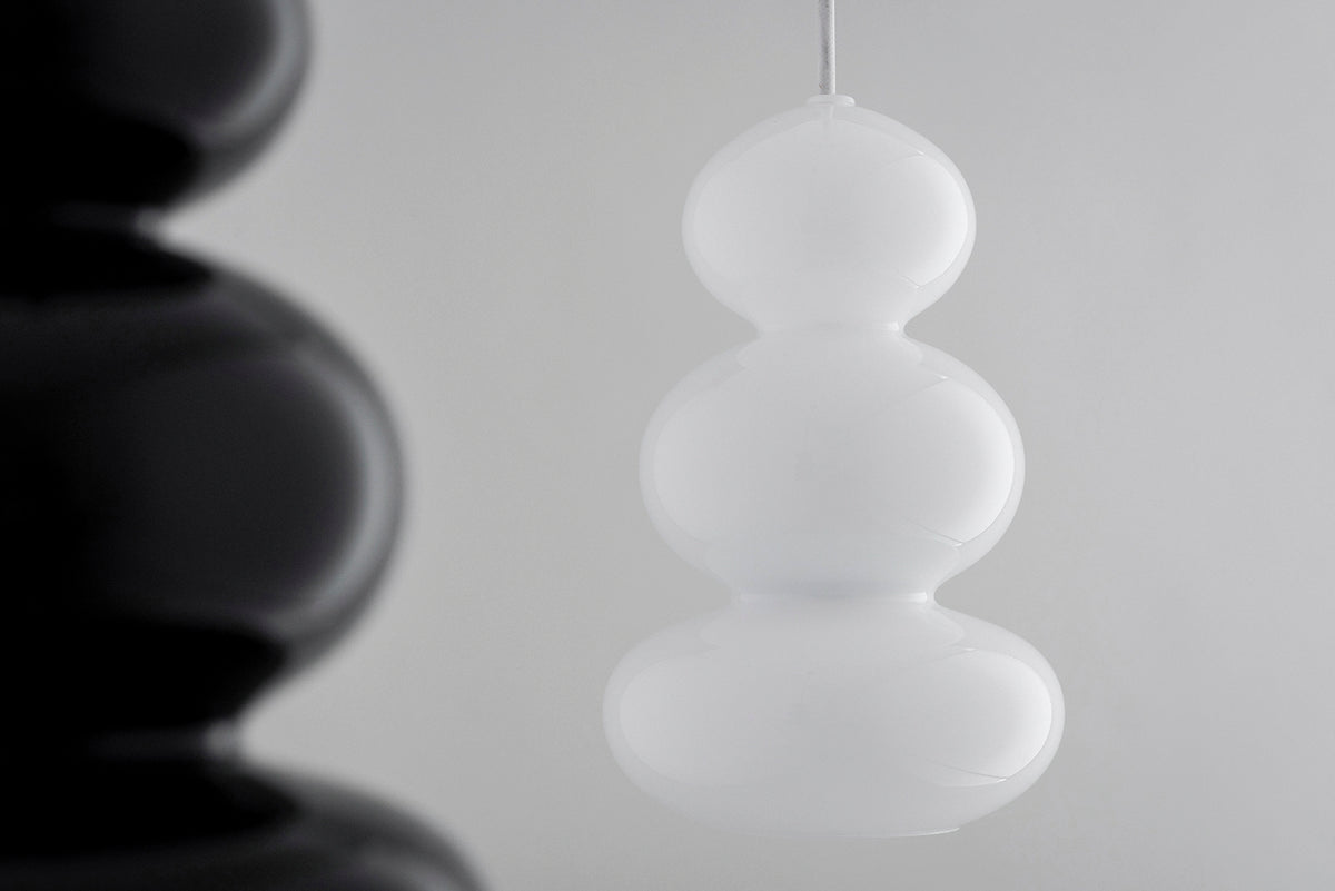 Gros plan sur une suspension blanche, une autre suspension noire floue en arrière-plan.