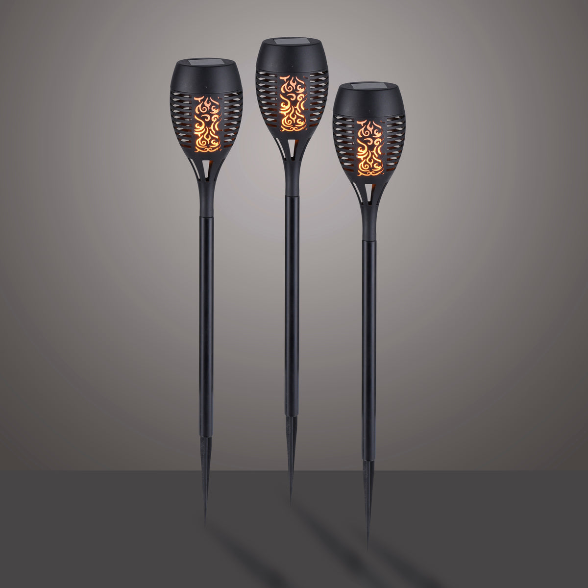 Trois piquets lumineux solaires noirs allumés sur fond dégradé gris.
